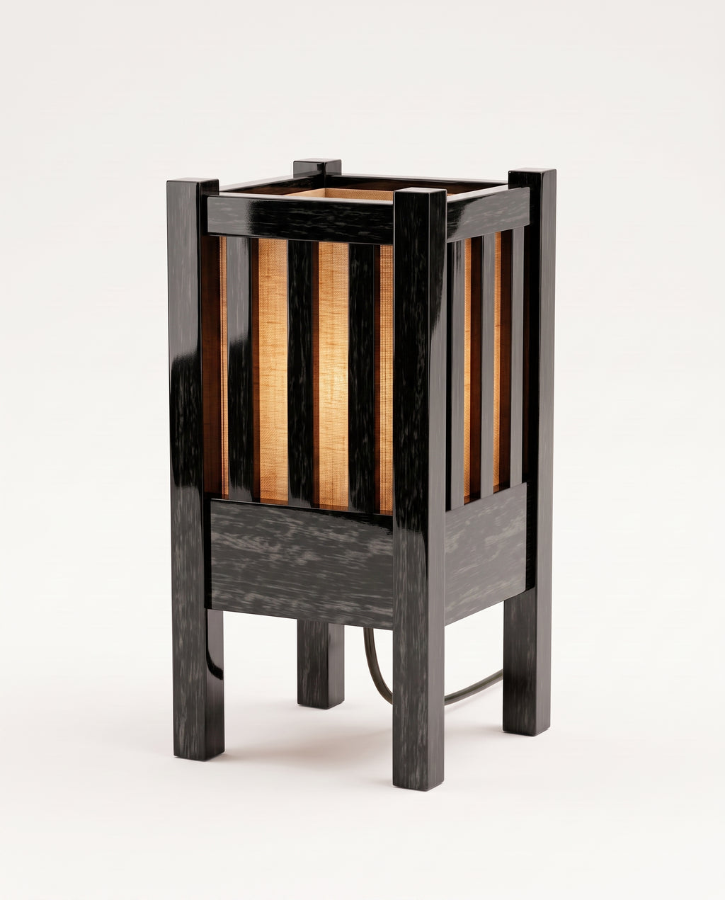Cardinal table lamp lit, warm light through the paper shade behind the black lacquer slats, Monde Singulier Editions, three-quarter view