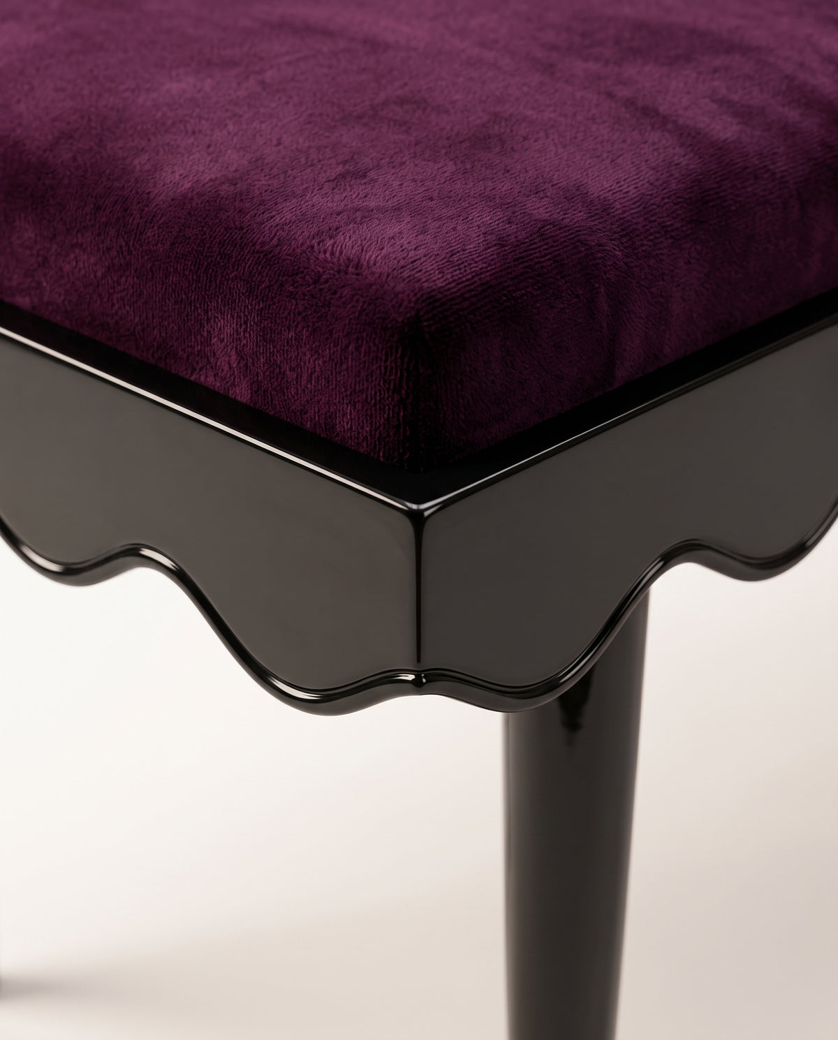Romance bench, close-up of the aubergine velvet seat, scalloped black lacquer skirt and tapered leg, Monde Singulier Editions