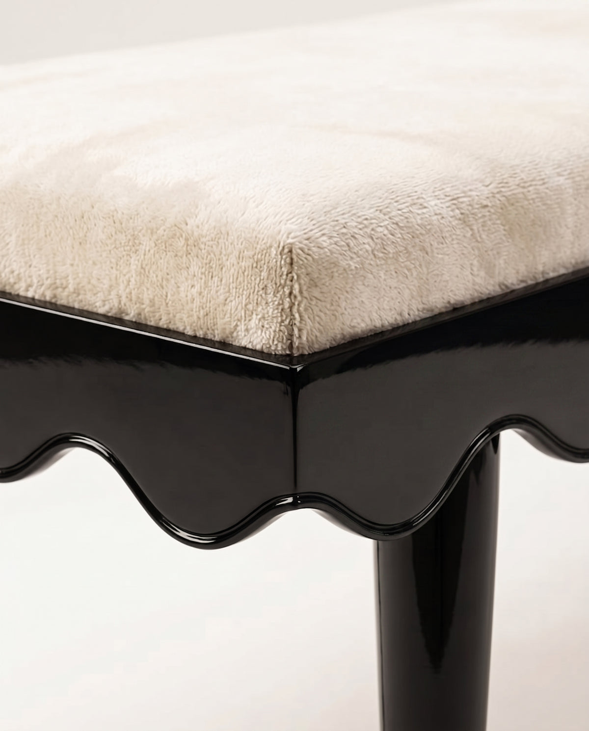 Romance bench, close-up of the ecru velvet seat, scalloped black lacquer skirt and tapered leg, Monde Singulier Editions