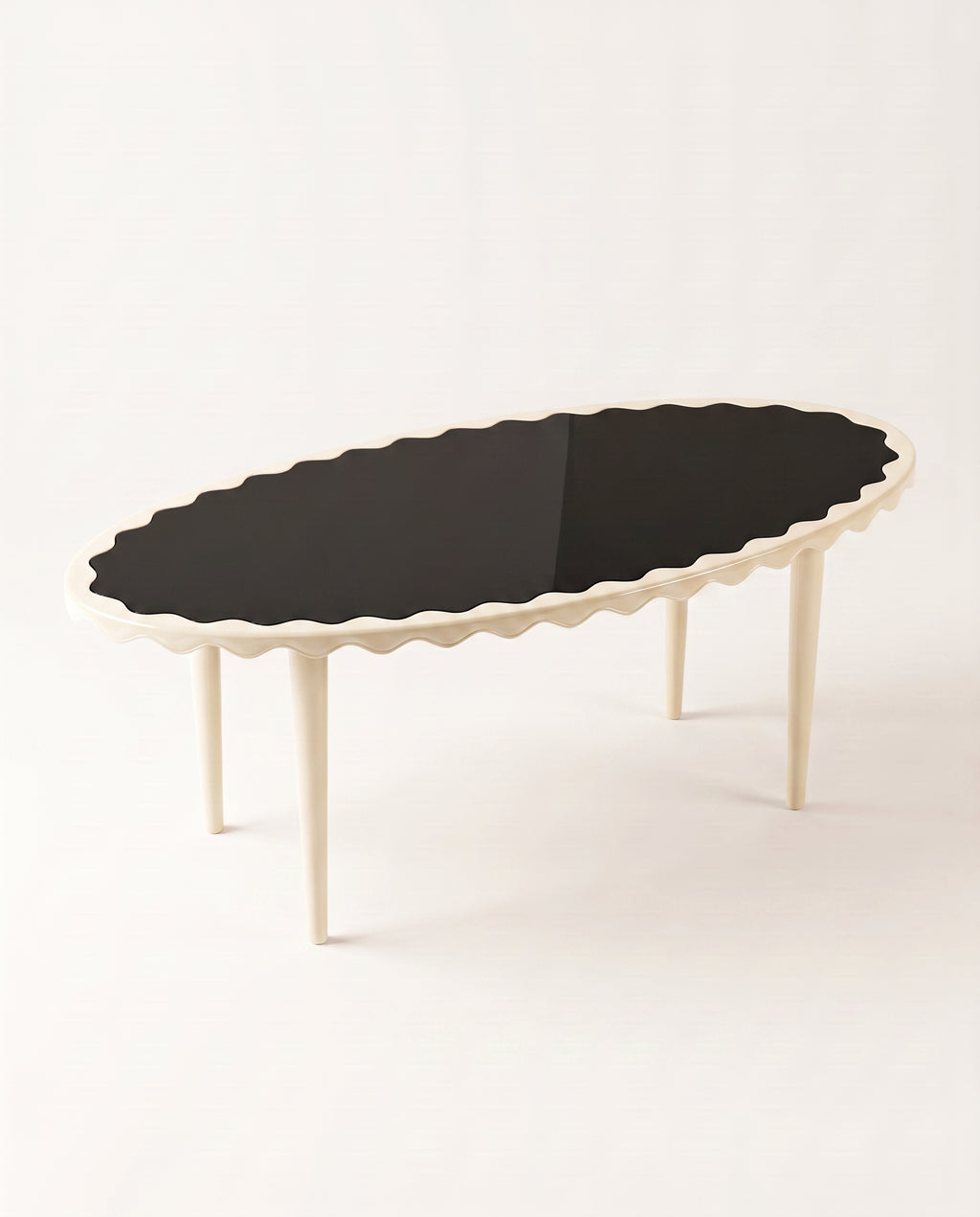 Romance oval dining table with black lacquer top and off-white scalloped apron, elevated view, Monde Singulier Editions