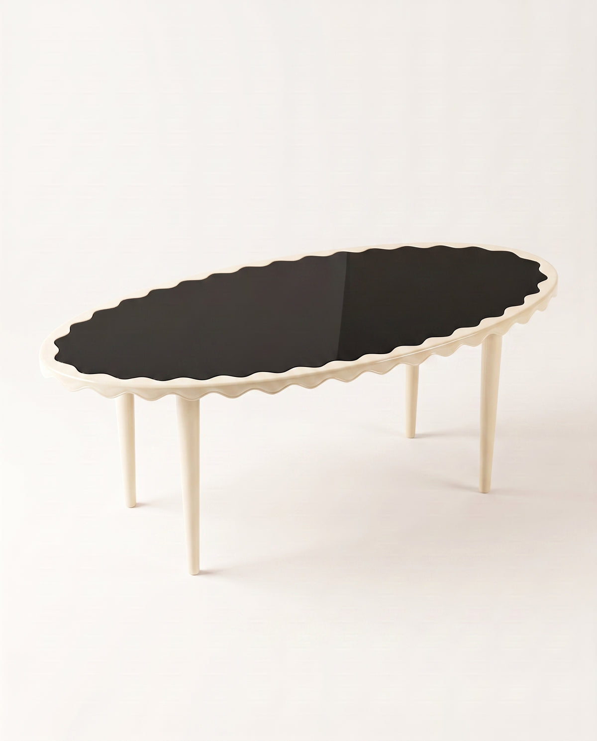 Romance oval dining table with black lacquer top and off-white scalloped apron, elevated view, Monde Singulier Editions