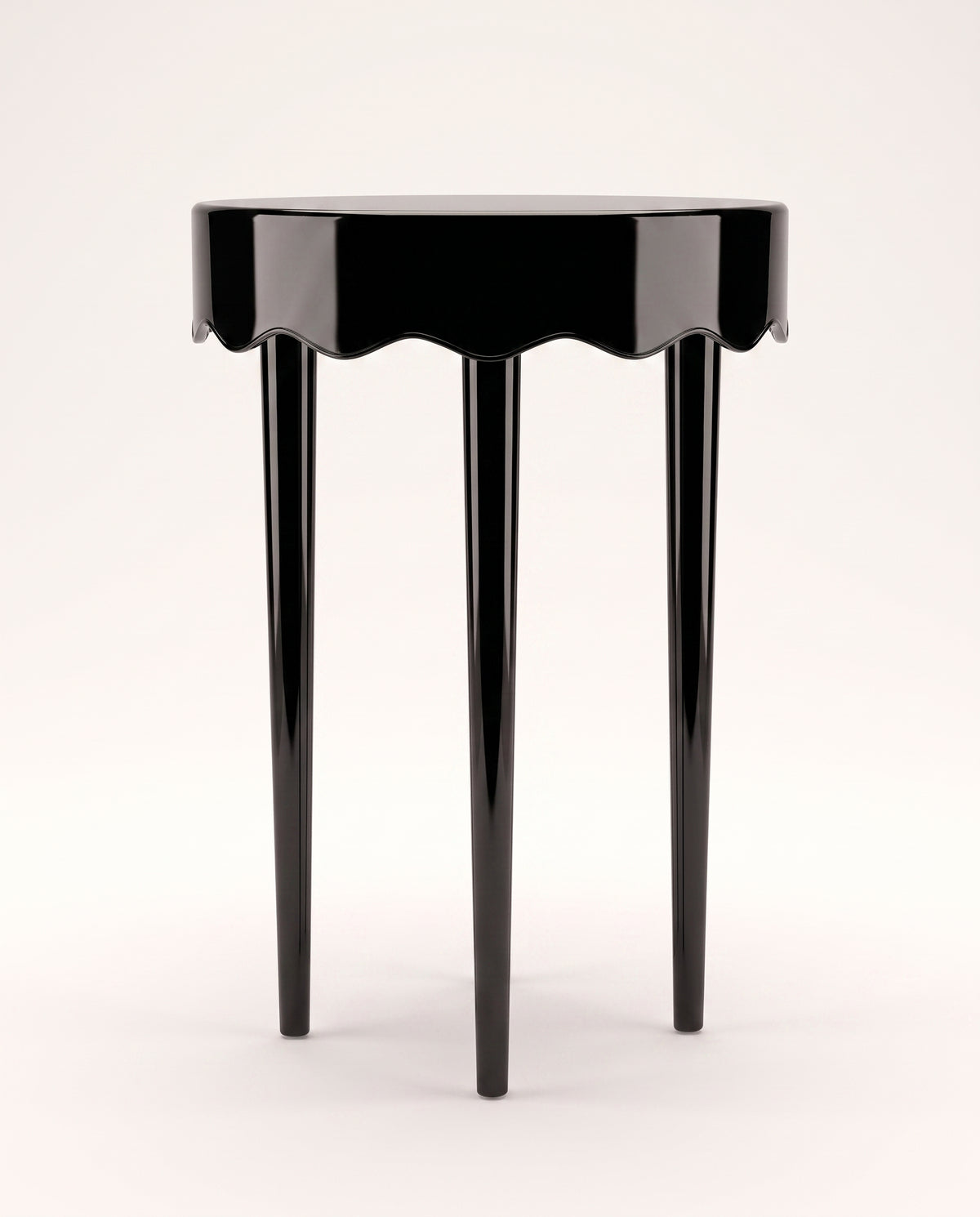 Romance round side table in black lacquer with scalloped apron and three tapered legs, Monde Singulier Editions, front view