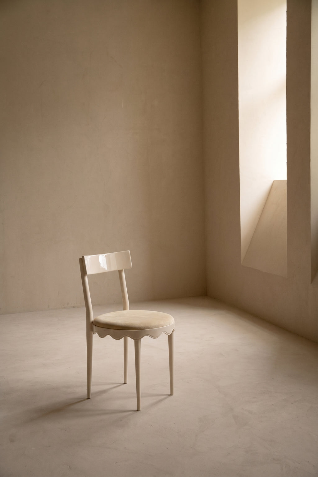 Chaise Romance blanc cassé seule dans une pièce baignée de lumière naturelle, Monde Singulier Editions