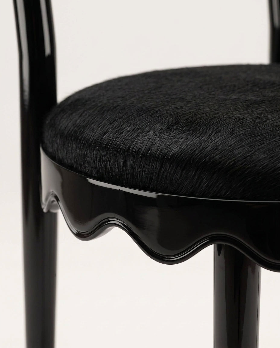 Romance chair in black, close-up of the round upholstered seat and scalloped black lacquer skirt, Monde Singulier Editions