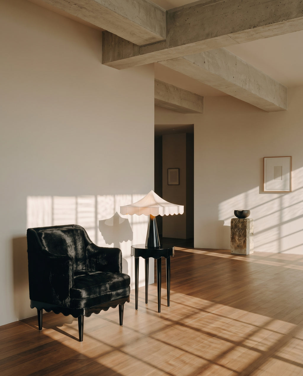 Fauteuil Romance noir et table d'appoint avec lampe Romance, dans un loft baigné de lumière, Monde Singulier Editions