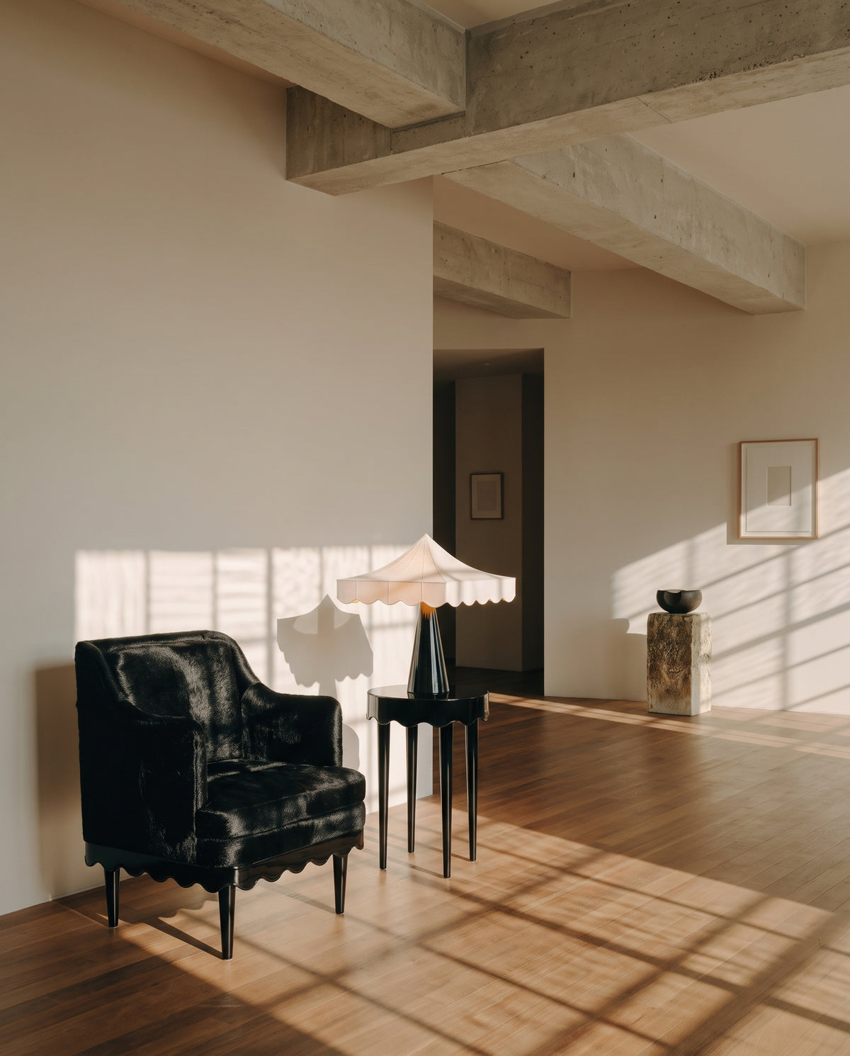 Fauteuil Romance noir et table d'appoint avec lampe Romance, dans un loft baigné de lumière, Monde Singulier Editions