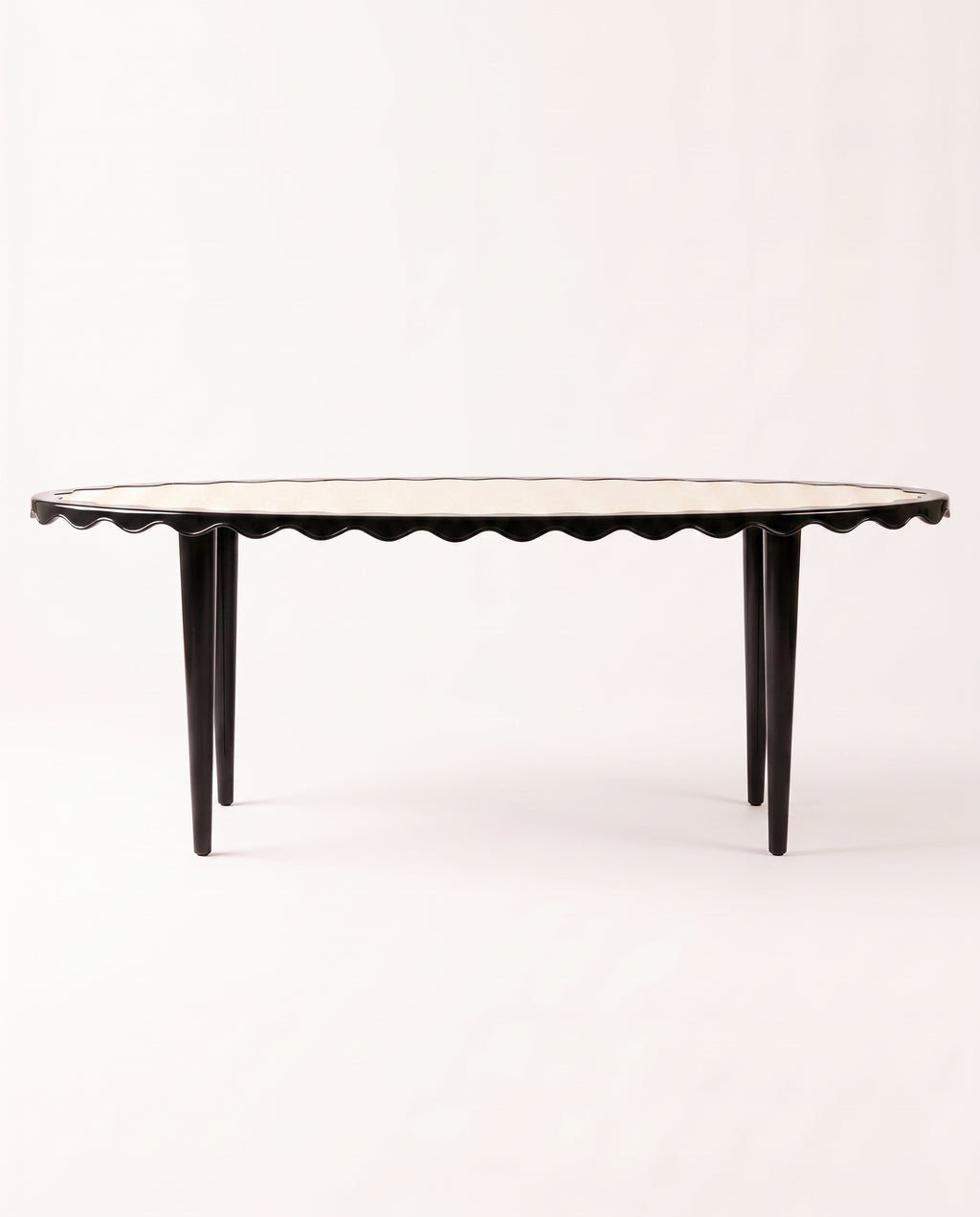 Romance oval dining table in black lacquer with scalloped apron and tapered legs, Monde Singulier Editions, three-quarter view