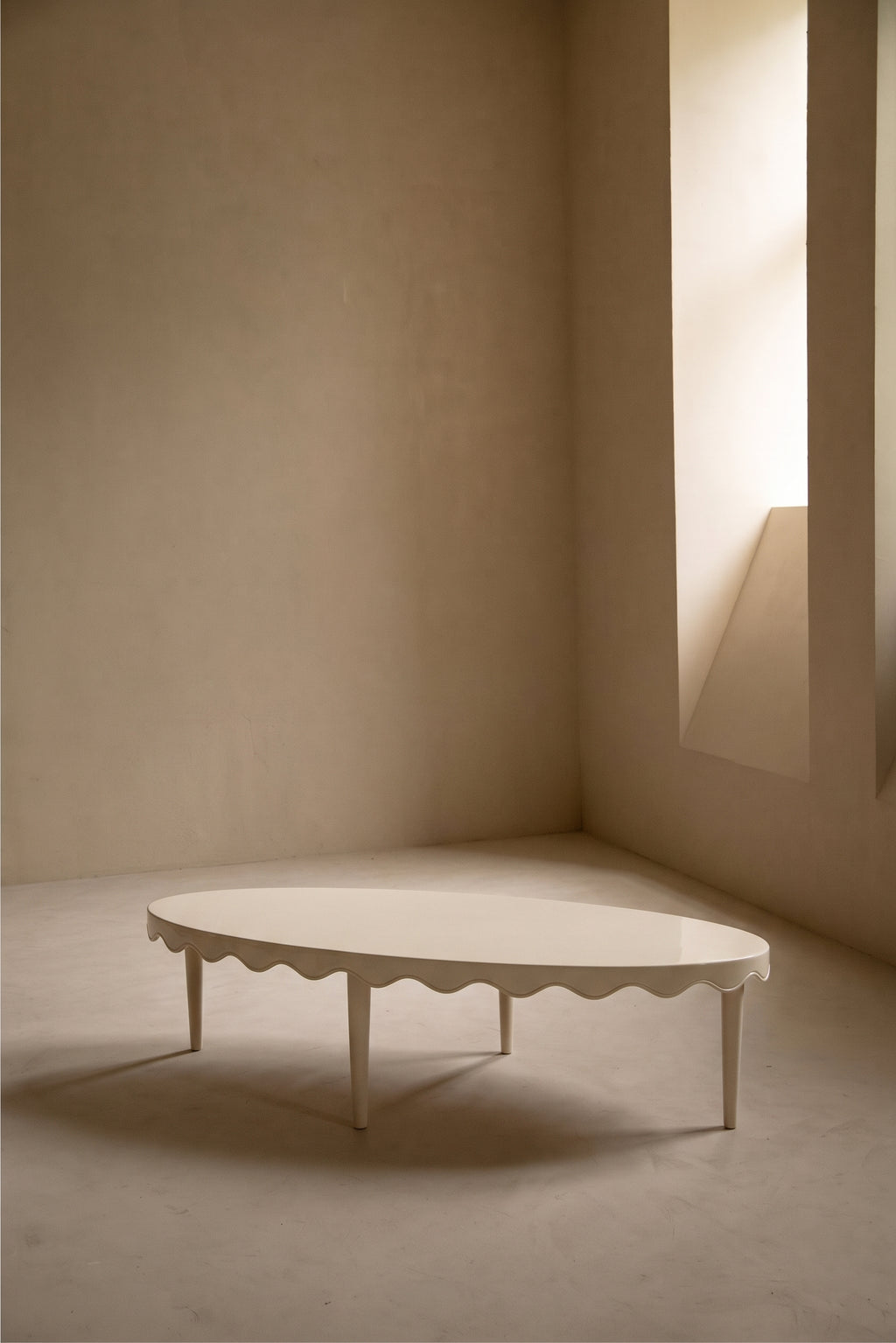 Table basse Romance ovale blanc cassé, bordure festonnée, dans une pièce lumineuse, Monde Singulier Editions