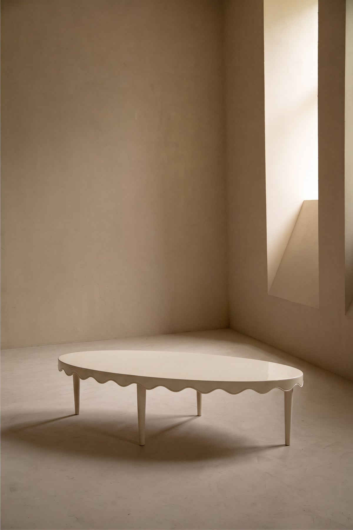 Table basse Romance ovale blanc cassé, bordure festonnée, dans une pièce lumineuse, Monde Singulier Editions